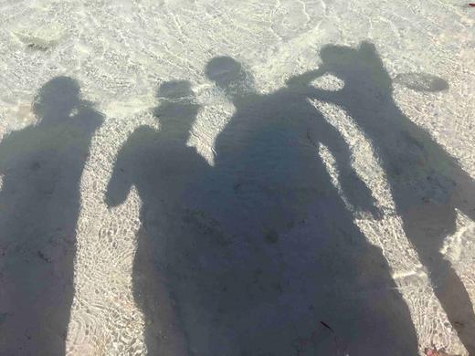 shadows of individuals against saltwater and sand