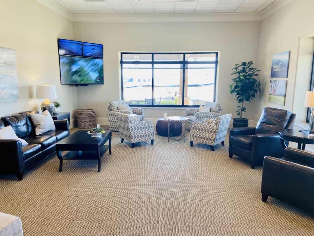 chairs sofas and big screen tv in the pilots lounge at Golden Isles Aviation at St Simons Island Airport